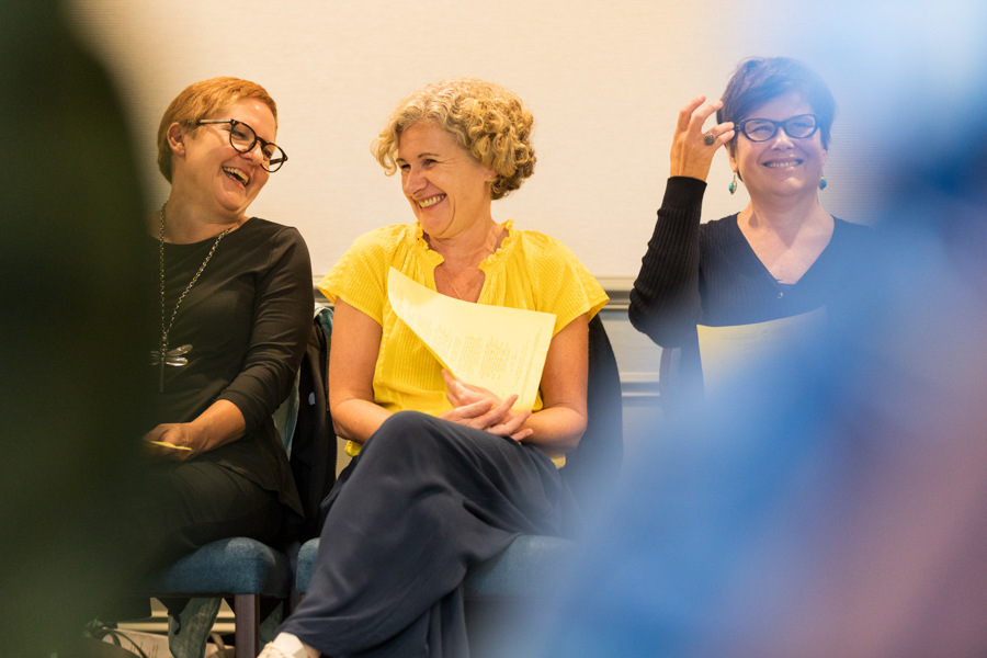 Two women, Global Warriors coaches sharing a moment of laughter. A third woman is also in the image. 